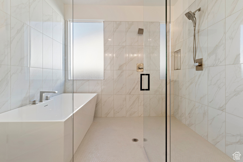 Full bathroom featuring a shower stall, a freestanding tub, and tile walls