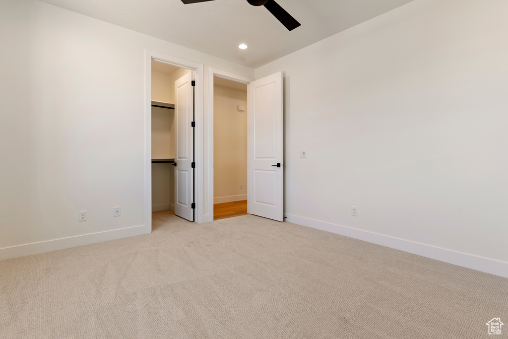 Unfurnished bedroom featuring light colored carpet, a spacious closet, baseboards, recessed lighting, and a closet