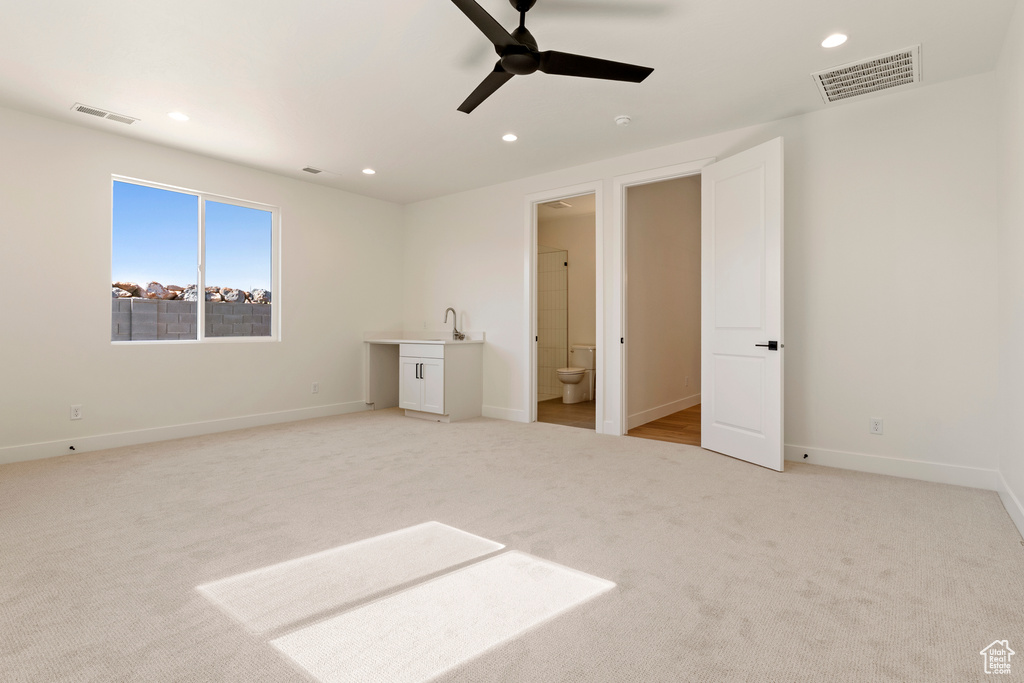Unfurnished bedroom featuring light carpet, recessed lighting, baseboards, ensuite bath, and a sink