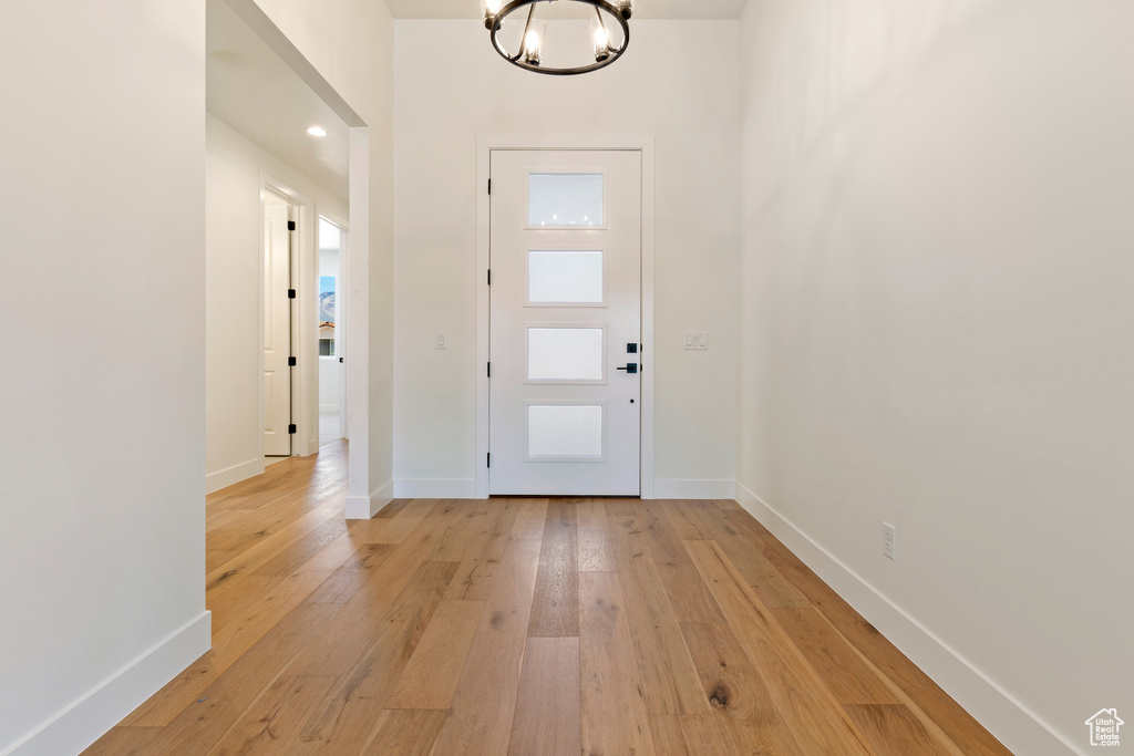 Entrance foyer featuring a chandelier, light wood-type flooring, and baseboards