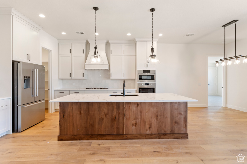 Kitchen with stainless steel appliances, a sink, recessed lighting, backsplash, and white cabinets