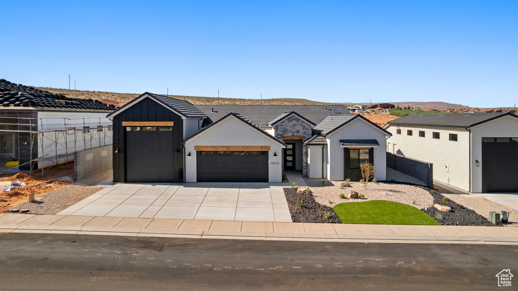 View of front of house featuring an attached garage, driveway, stucco siding, a tiled roof, and fence