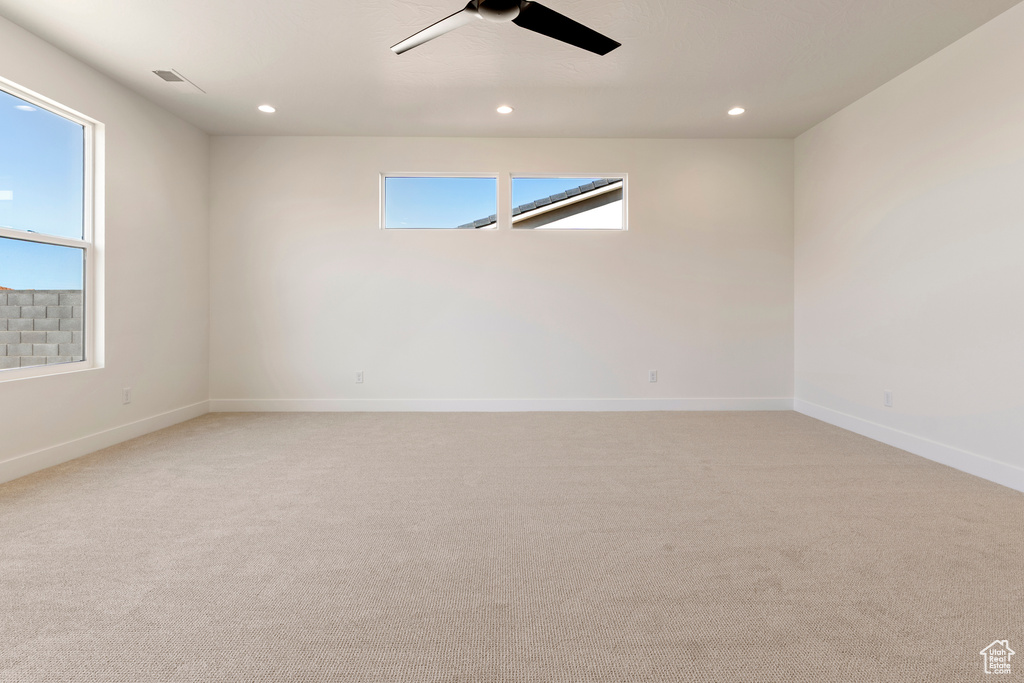 Empty room featuring a ceiling fan, light colored carpet, plenty of natural light, baseboards, and recessed lighting