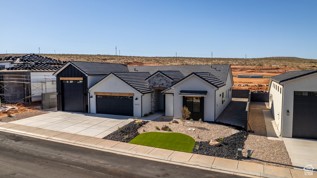 Modern inspired farmhouse with an attached garage, concrete driveway, stucco siding, and fence