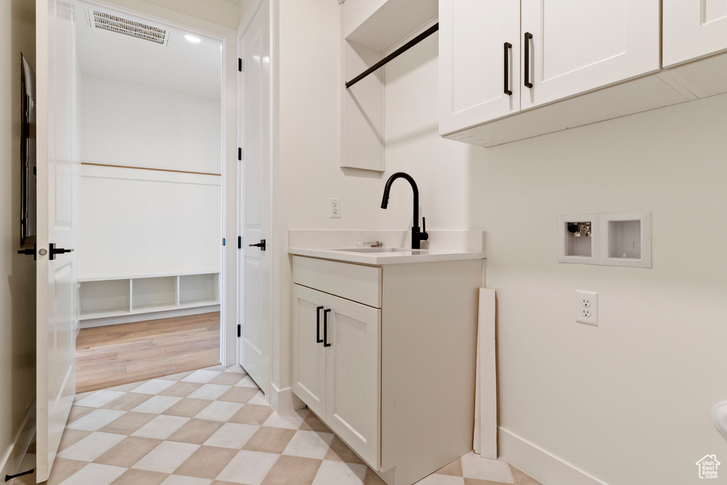 Laundry room with hookup for a washing machine, cabinet space, light floors, and baseboards
