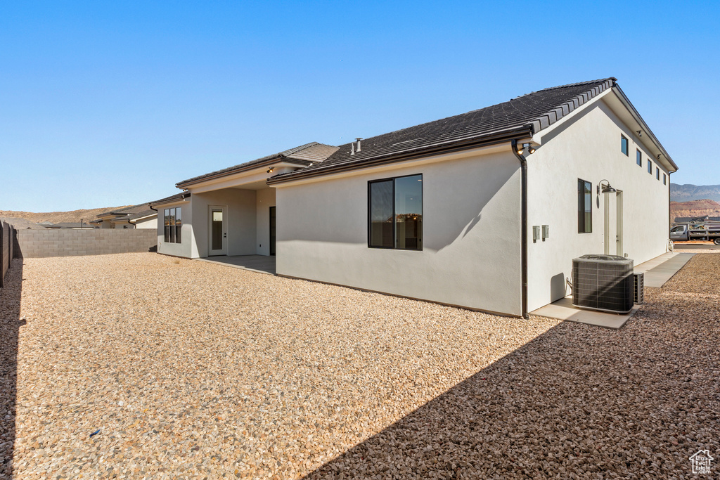Rear view of property with a fenced backyard, central AC, stucco siding, and a patio area