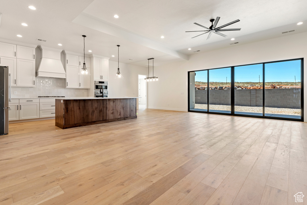 Kitchen featuring custom exhaust hood, open floor plan, recessed lighting, stainless steel appliances, and backsplash