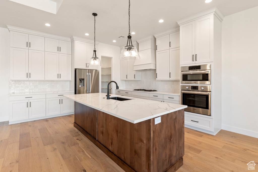 Kitchen featuring stainless steel appliances, a sink, recessed lighting, light wood finished floors, and tasteful backsplash