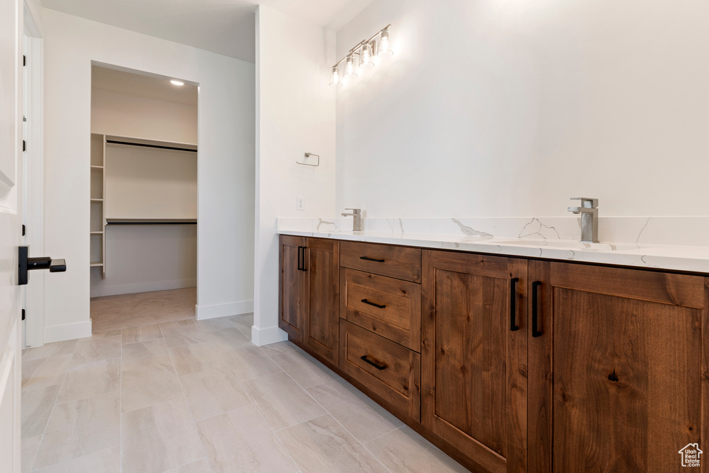 Full bath with a walk in closet, a sink, marble finish floors, and baseboards