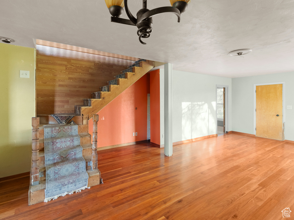 Unfurnished living room with wood finished floors, stairs, and baseboards