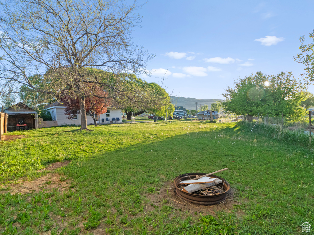 View of green lawn with a fire pit and a mountain view