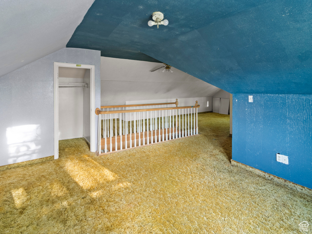 Additional living space featuring vaulted ceiling, carpet flooring, a ceiling fan, and baseboards