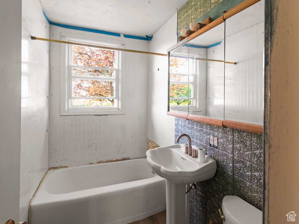 Full bathroom with toilet and tile walls