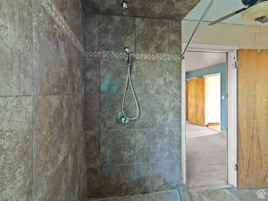Bathroom featuring tiled shower and a ceiling fan