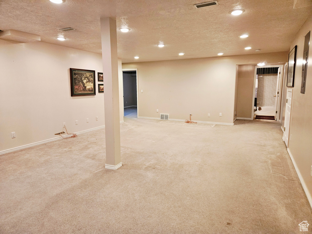 Finished below grade area with light carpet, a textured ceiling, recessed lighting, and baseboards