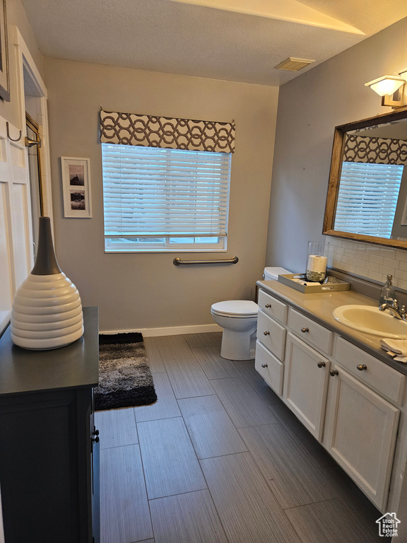 Bathroom with decorative backsplash, toilet, vanity, wood finished floors, and baseboards