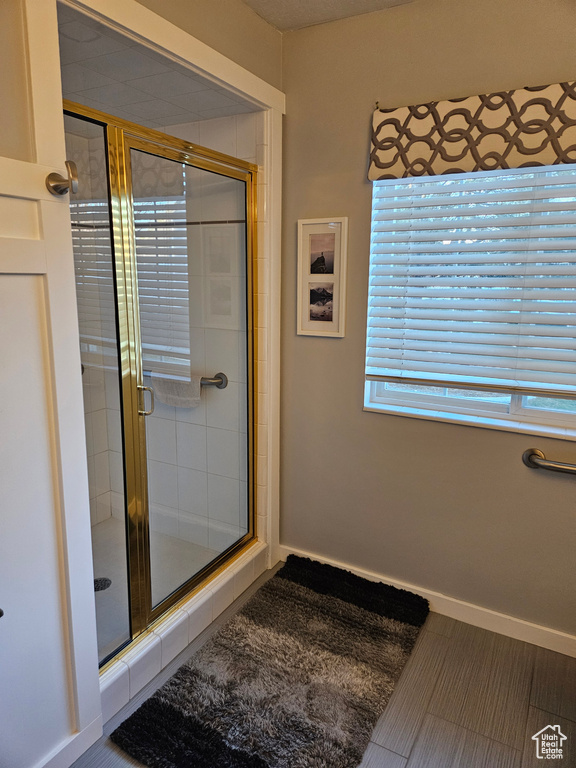 Full bathroom featuring a shower stall and baseboards