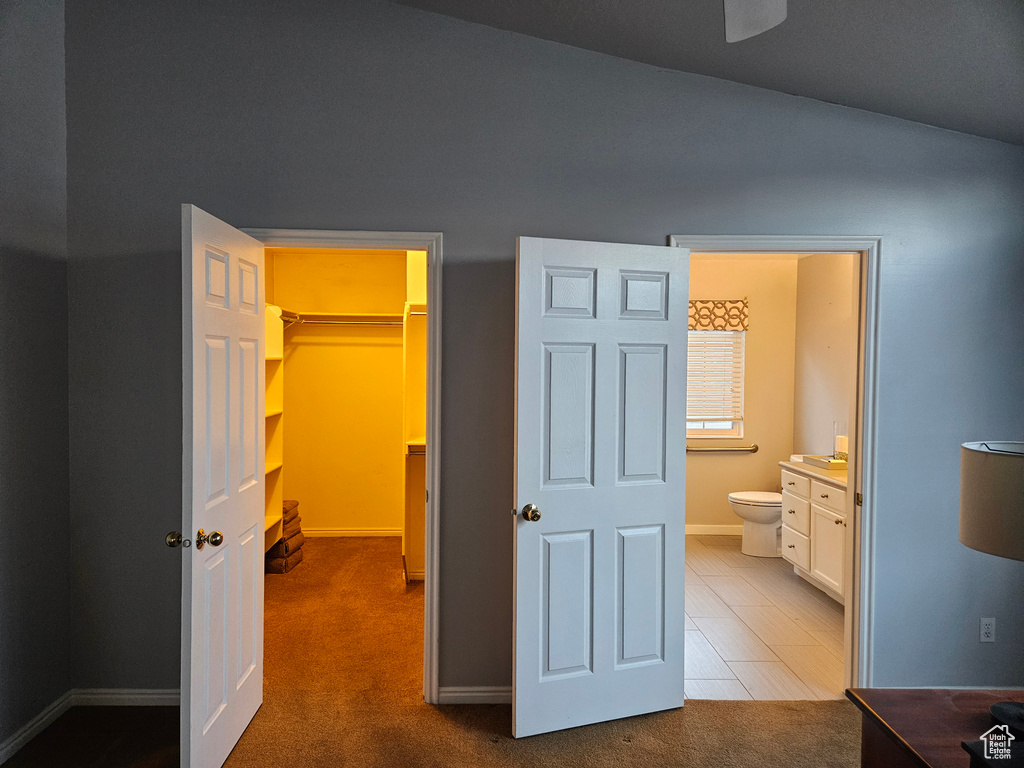 Hallway featuring baseboards, vaulted ceiling, and carpet floors
