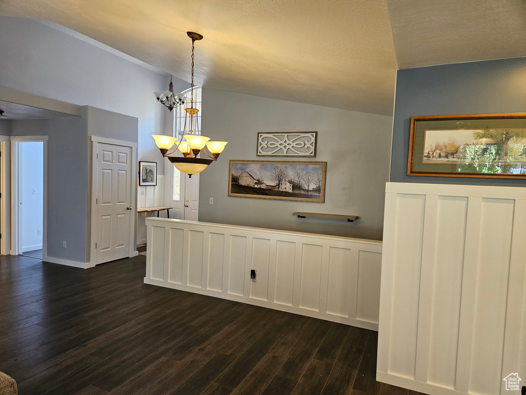 Dining room featuring dark wood-style flooring, a chandelier, and vaulted ceiling