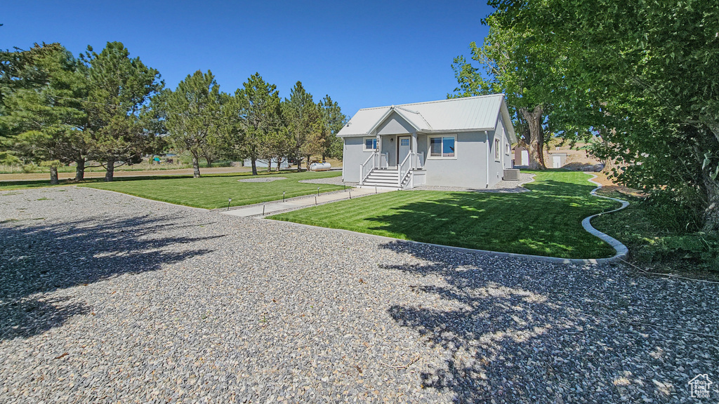 View of front of home featuring a front lawn, metal roof, and stucco siding