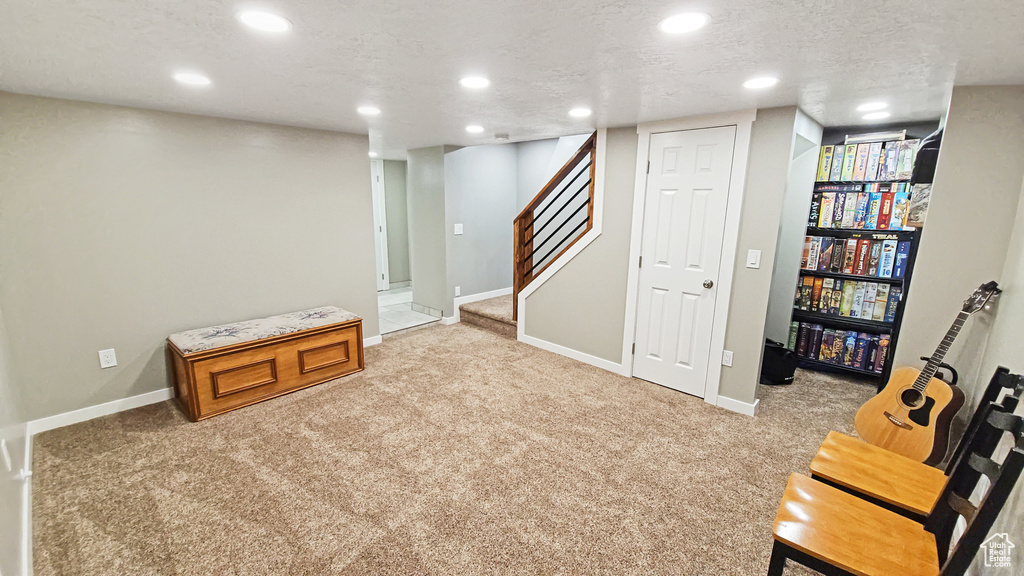 Finished below grade area with light carpet, baseboards, stairs, and recessed lighting