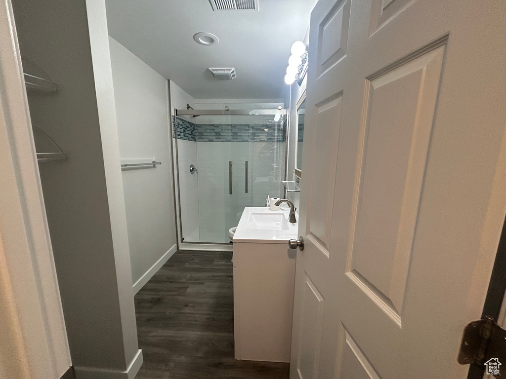 Full bathroom featuring a shower stall, vanity, wood finished floors, baseboards, and recessed lighting