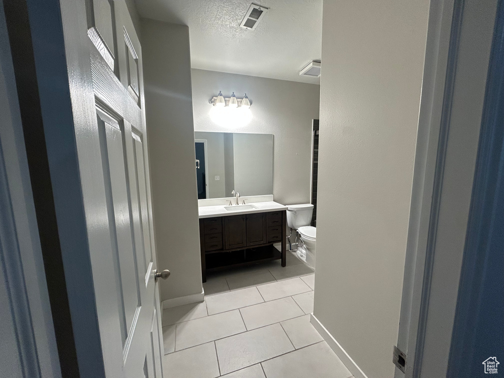Bathroom with toilet, tile patterned flooring, vanity, a textured ceiling, and baseboards