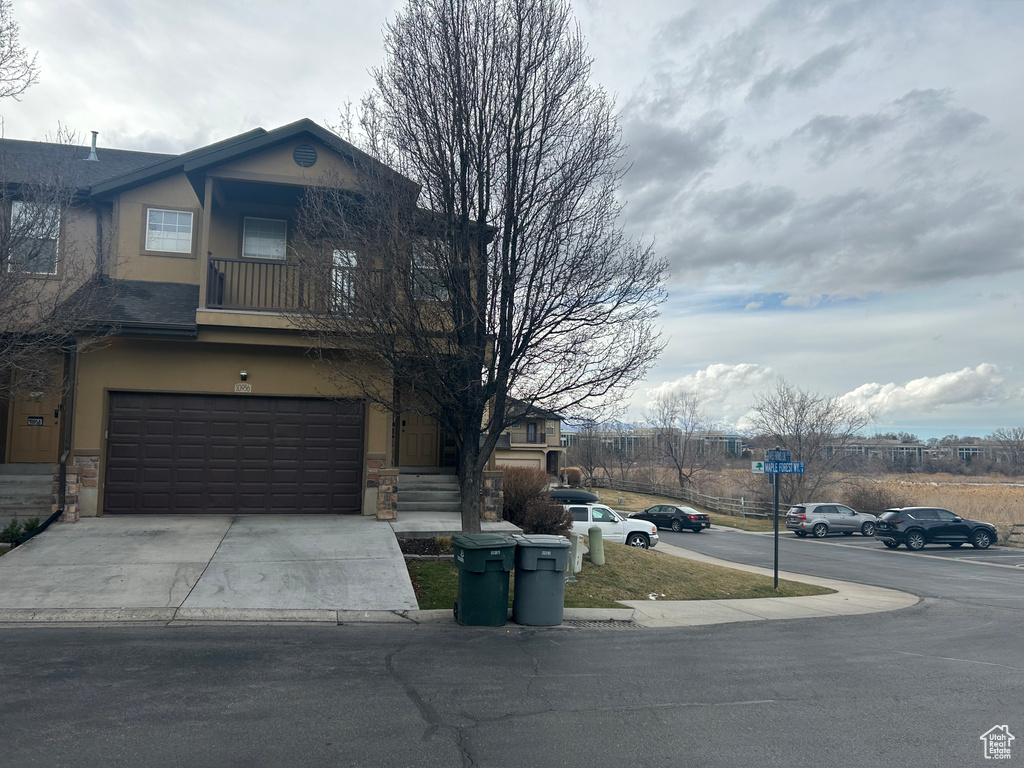 View of front of home featuring stucco siding, an attached garage, stone siding, and driveway