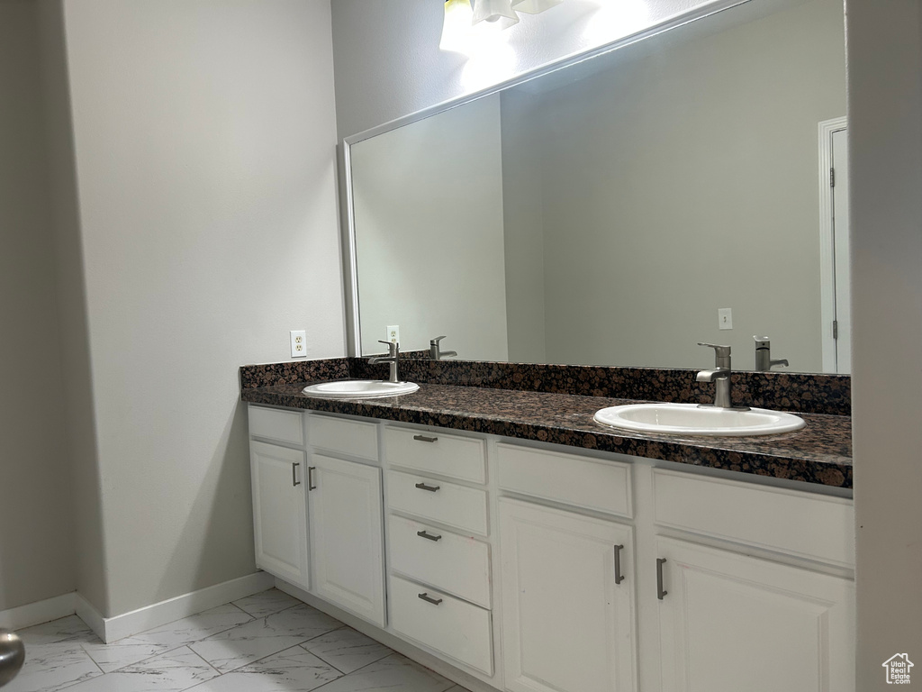 Bathroom with marble finish flooring, double vanity, and baseboards