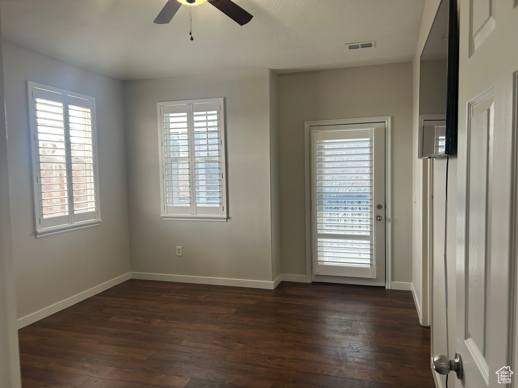 Unfurnished room with a ceiling fan, dark wood-type flooring, and baseboards
