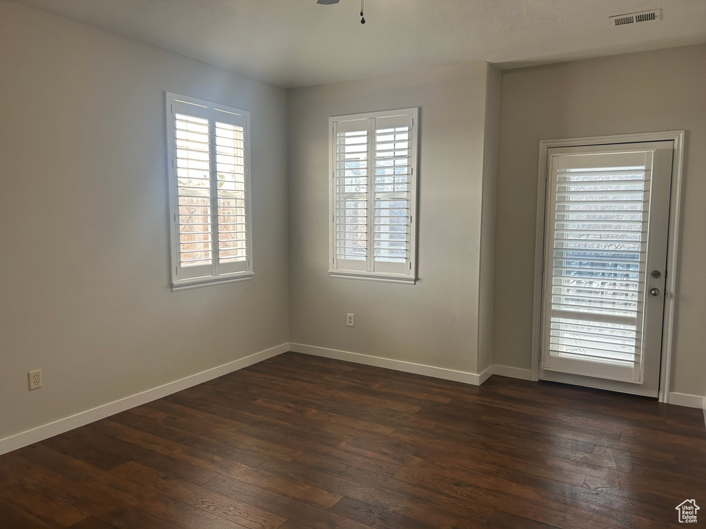 Spare room featuring dark wood-style flooring, baseboards, and ceiling fan