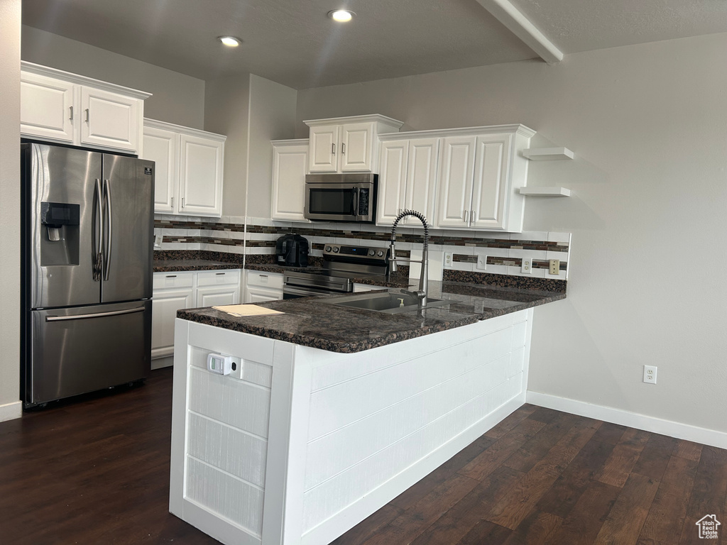 Kitchen with appliances with stainless steel finishes, a sink, open shelves, a peninsula, and white cabinetry
