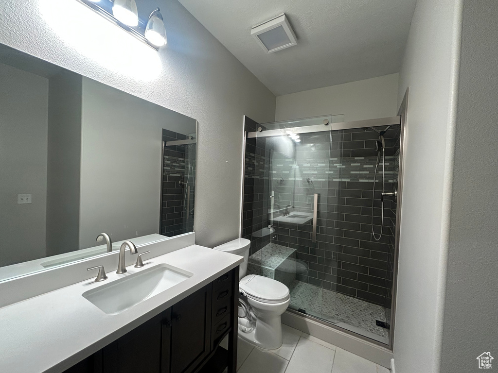 Full bathroom featuring toilet, tile patterned floors, a stall shower, and vanity