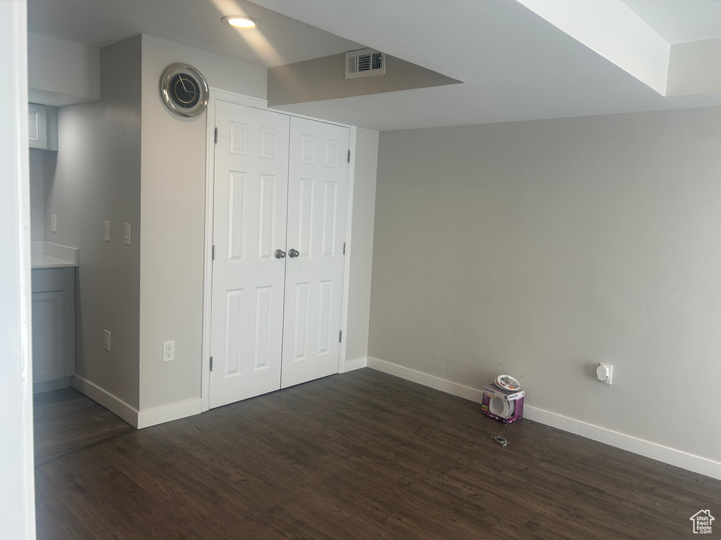 Unfurnished bedroom with dark wood-style floors, baseboards, and a closet