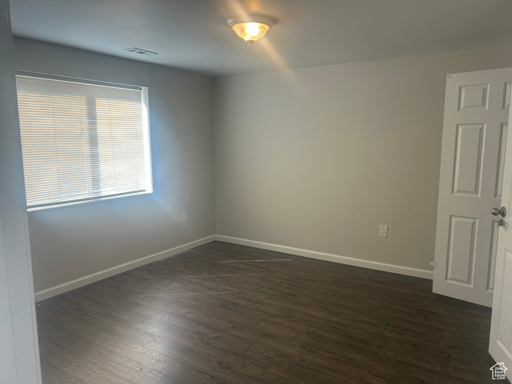 Spare room featuring baseboards and dark wood-style floors