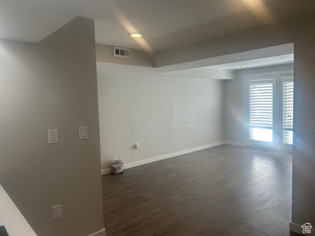 Empty room featuring baseboards and dark wood-type flooring
