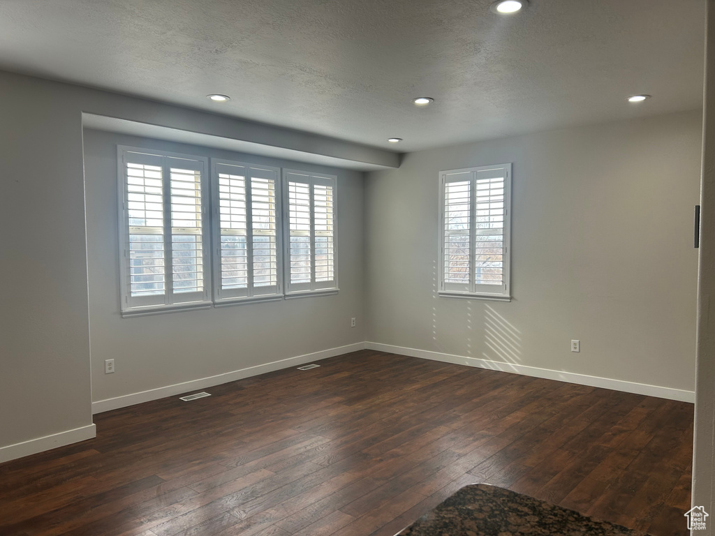 Spare room with dark wood finished floors, recessed lighting, baseboards, and a textured ceiling