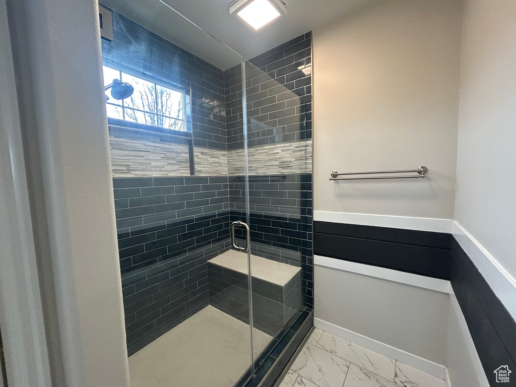 Full bath featuring a shower stall and marble finish flooring