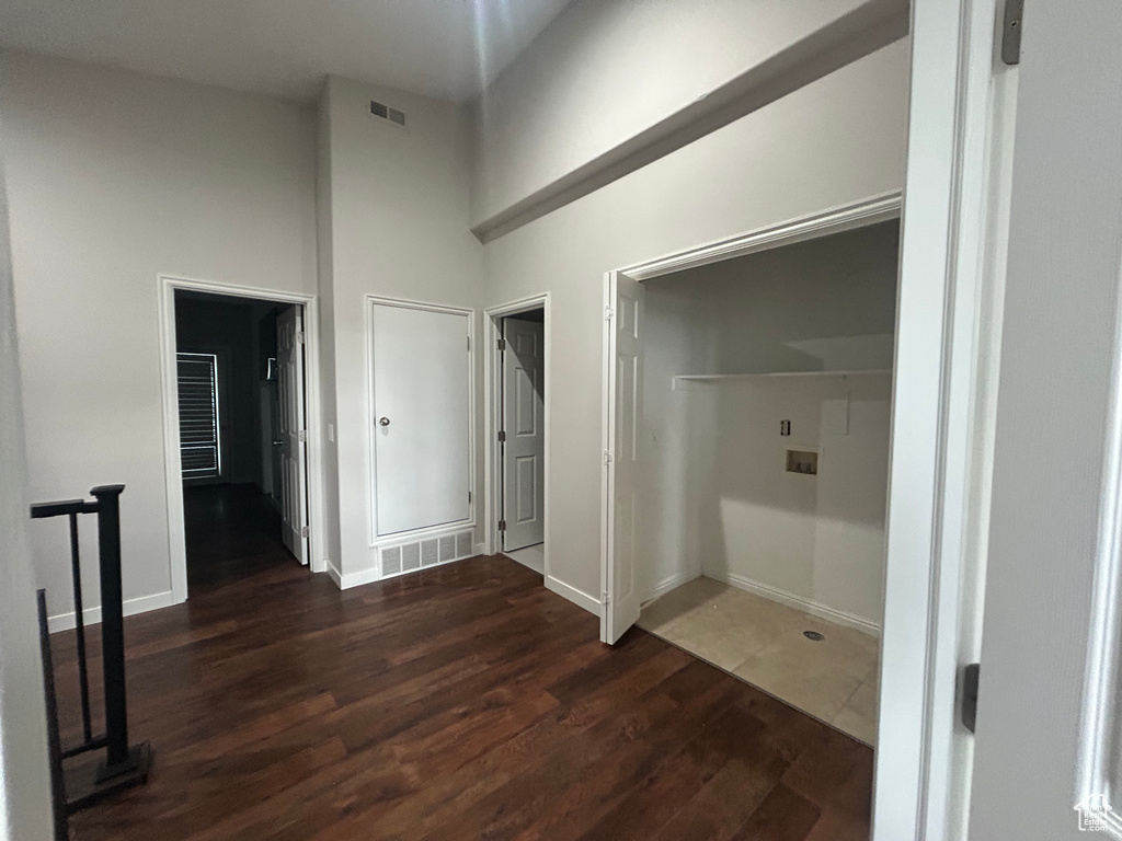Hallway featuring wood finished floors, a high ceiling, and baseboards
