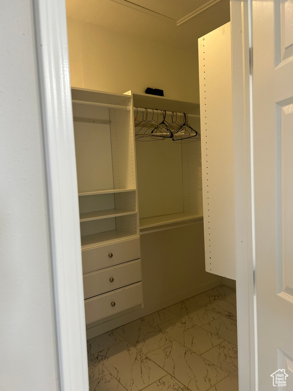 Spacious closet featuring light marble finish floors