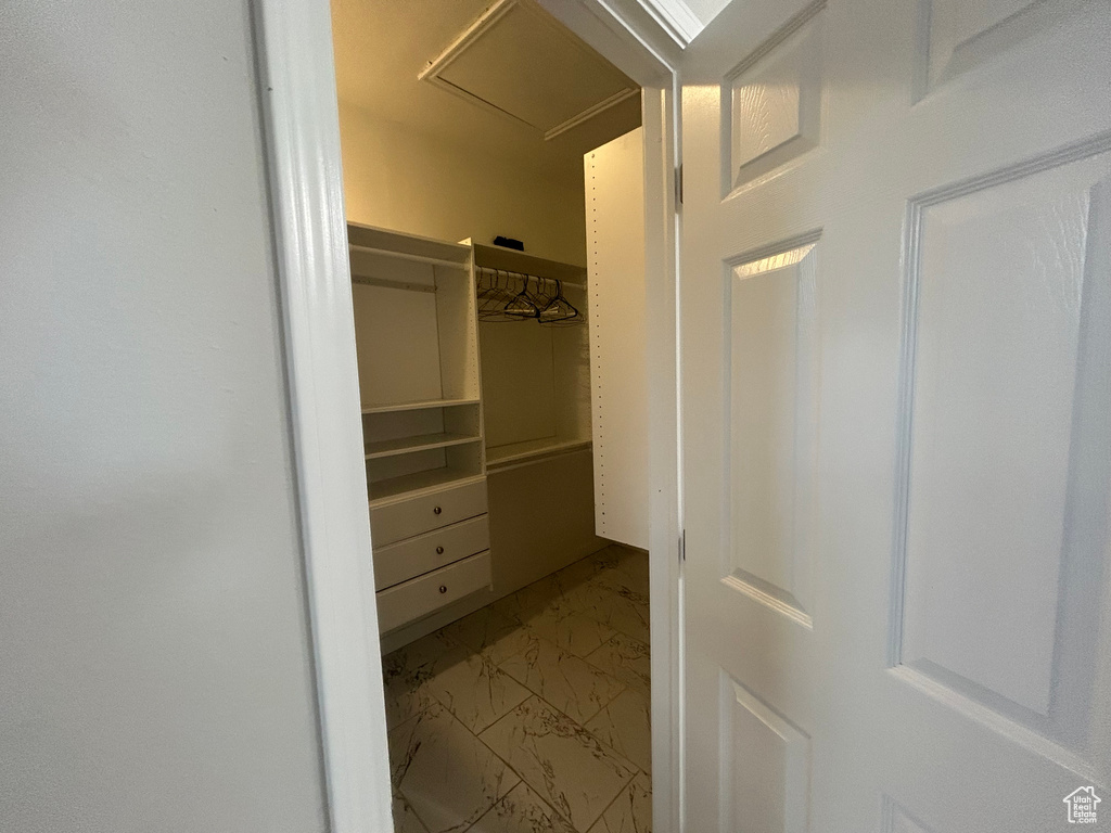 Spacious closet with light marble finish floors and attic access