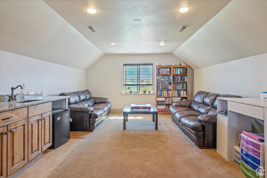 Living area with lofted ceiling, a textured ceiling, and light colored carpet
