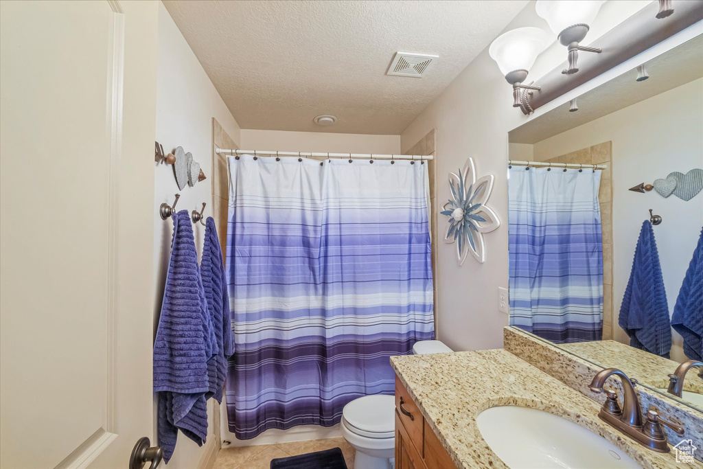 Bathroom with toilet, a textured ceiling, vanity, and a shower with curtain