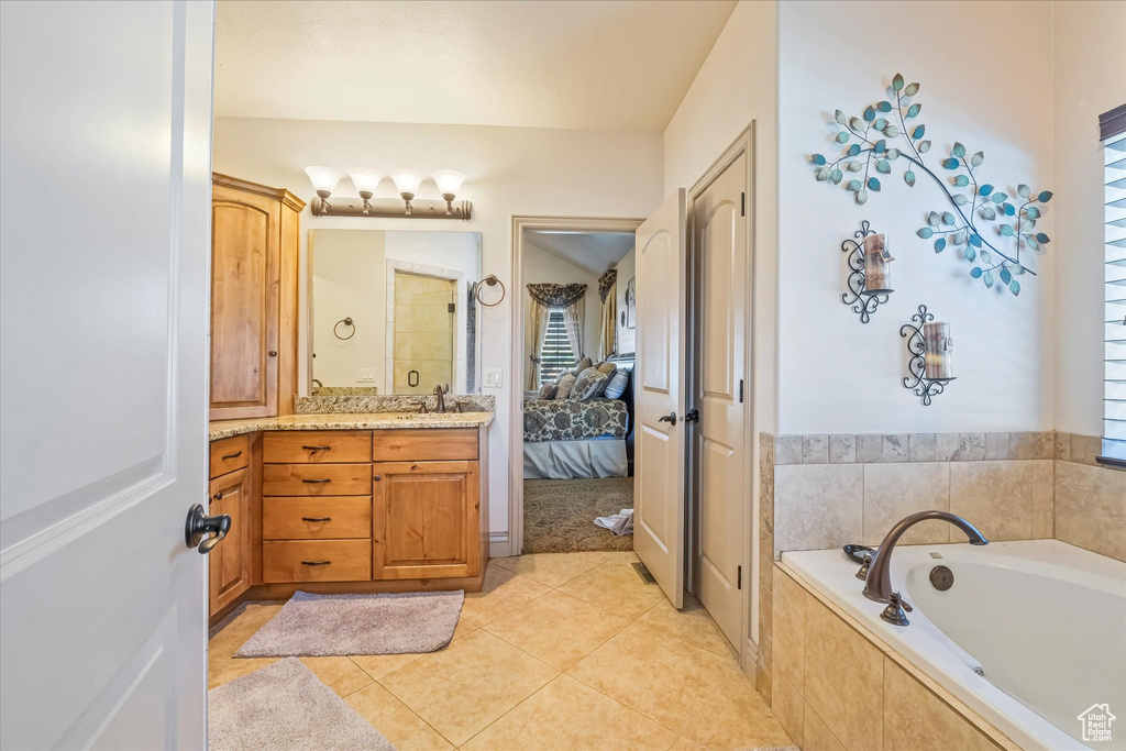 Bathroom with healthy amount of natural light, ensuite bathroom, a bath, and vanity
