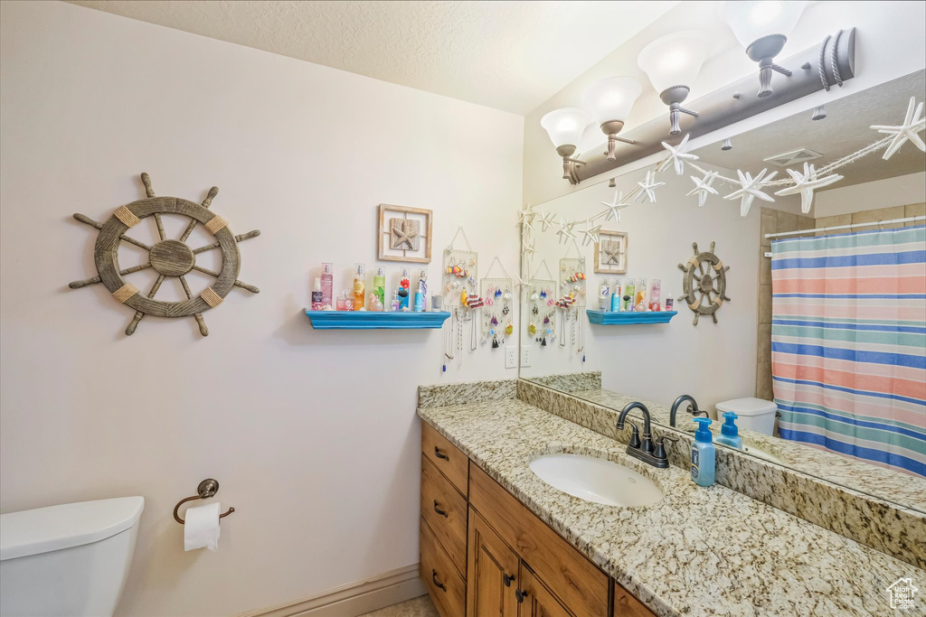 Full bathroom with toilet, vanity, a shower with curtain, and baseboards