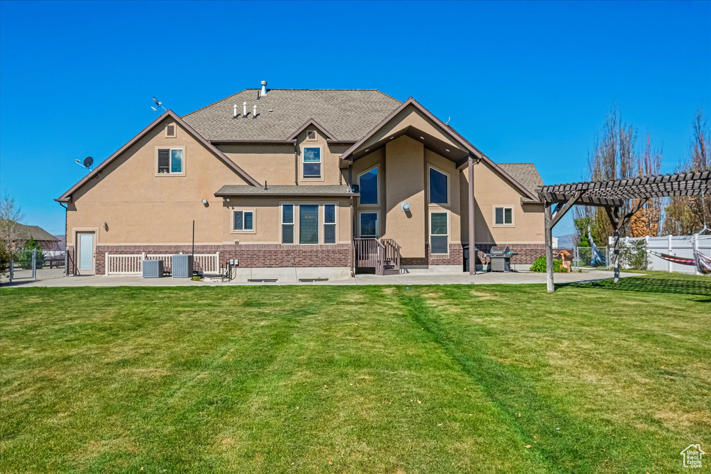 Rear view of house with a pergola, brick siding, stucco siding, and a patio area