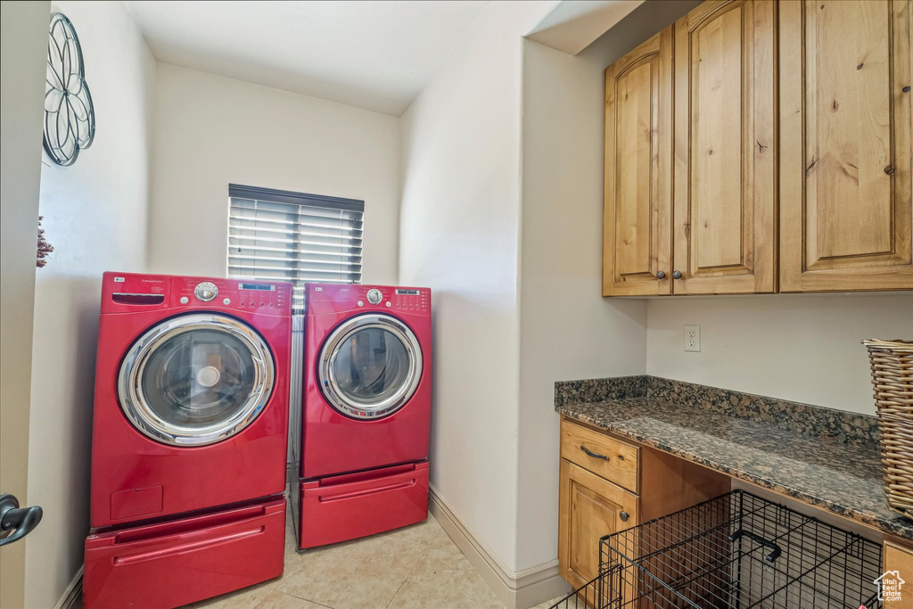 Laundry area featuring washing machine and dryer, cabinet space, baseboards, and tile patterned floors