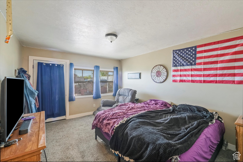 Bedroom featuring carpet, baseboards, and a textured ceiling