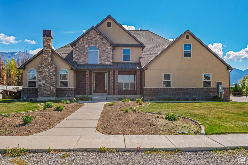 View of front of home featuring a front yard, stucco siding, a chimney, and brick siding