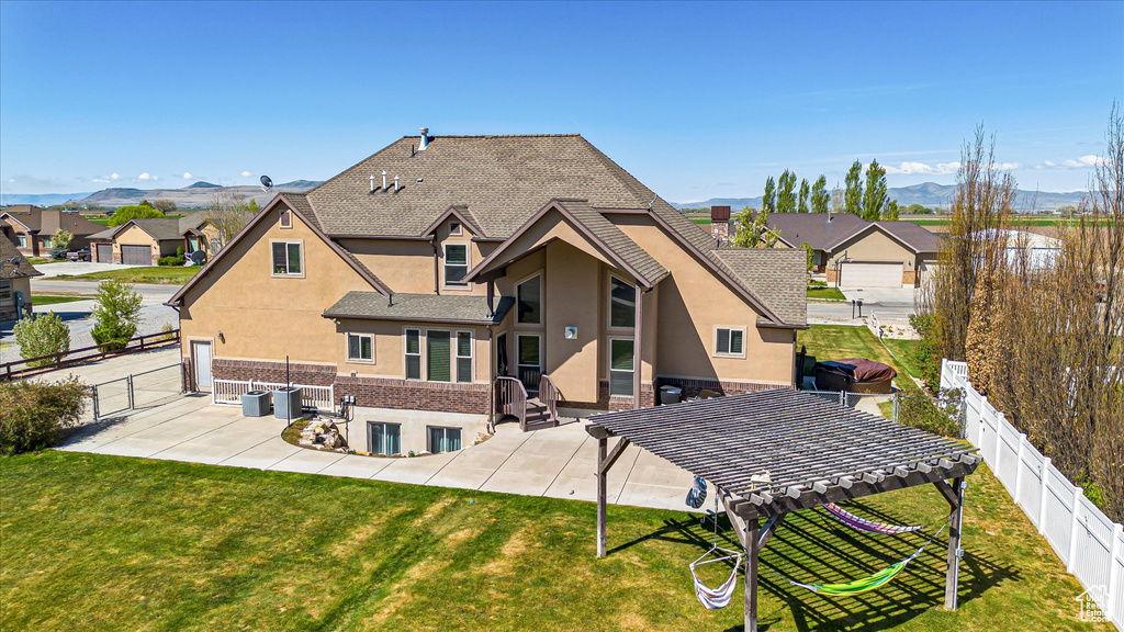 Rear view of property with stucco siding, a patio, a mountain view, and roof with shingles
